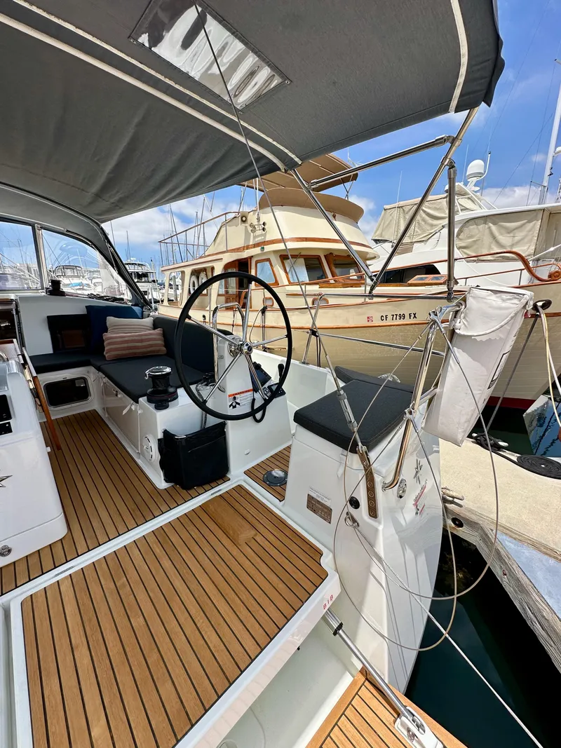 Slide: The Image of 2021 Jeanneau Sun Odyssey 440 sailboat cockpit with wooden deck and steering wheel in marina. - 18