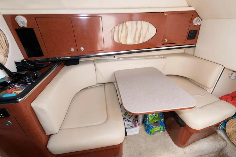 Slide: The Image of 2005 Sea Ray 290 Amberjack cabin interior with beige seating and wooden cabinetry. - 10