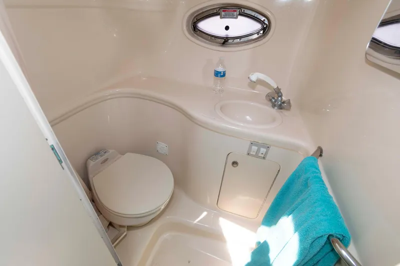 Slide: The Image of 2005 Sea Ray 290 Amberjack bathroom with toilet, sink, and porthole window. - 11