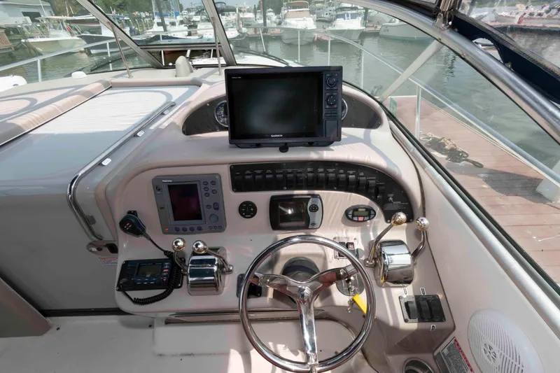 Slide: The Image of 2005 Sea Ray 290 Amberjack helm with navigation equipment and steering wheel in marina setting. - 6