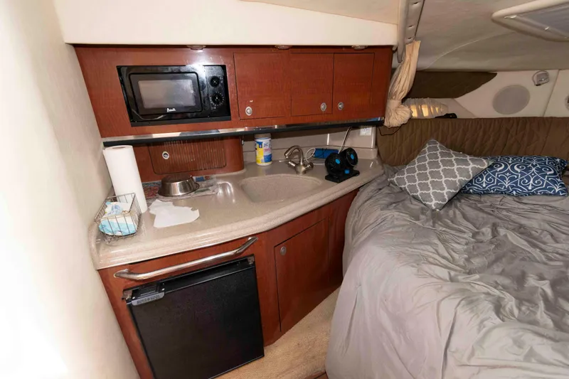 Slide: The Image of 2005 Sea Ray 290 Amberjack cabin interior with kitchenette and cozy sleeping area. - 9