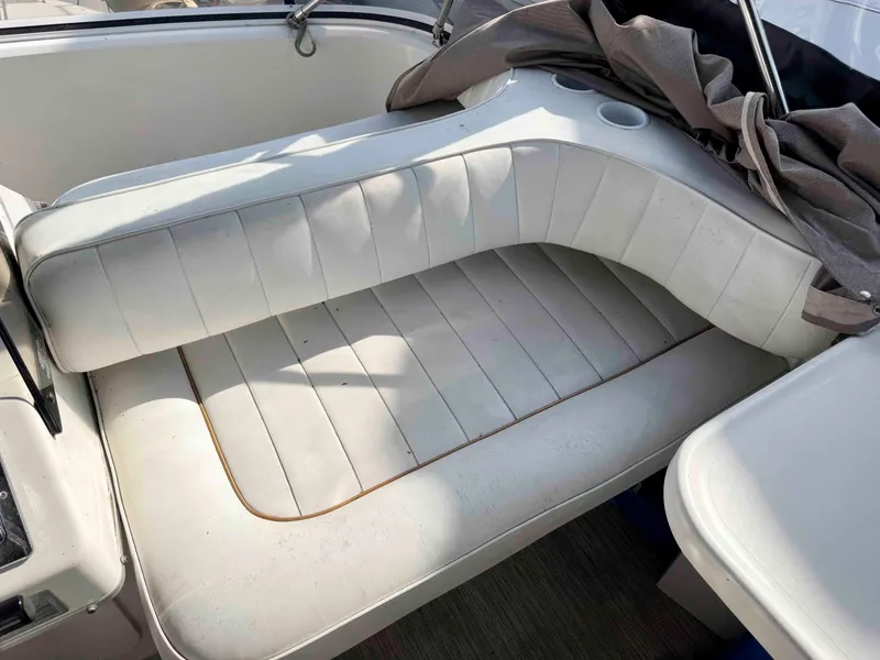 Slide: The Image of 1998 Sea Ray 440 Express Bridge interior seating with white upholstery and cup holders. - 11