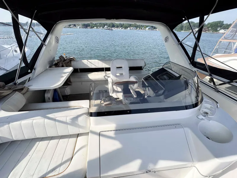 Slide: The Image of 1998 Sea Ray 440 Express Bridge interior with seating and helm, overlooking a serene water view. - 13