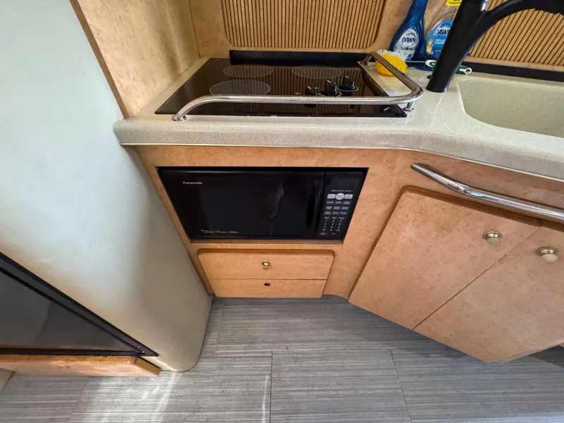 Slide: The Image of 1998 Sea Ray 440 Express Bridge kitchen with microwave, stove, and sink. - 17