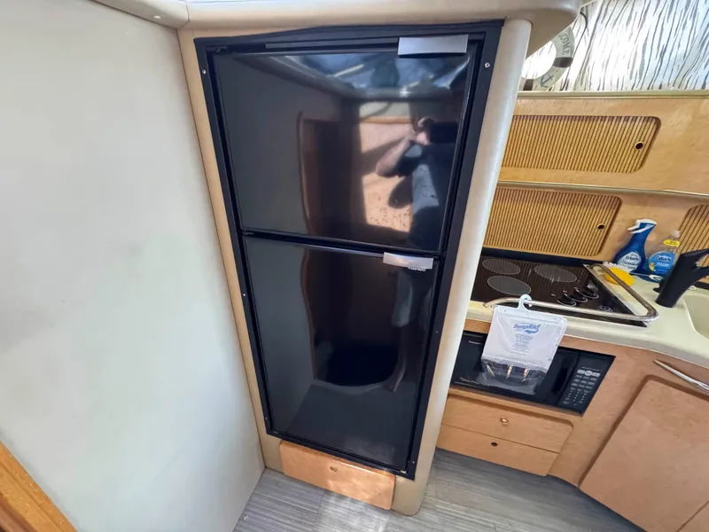 Slide: The Image of 1998 Sea Ray 440 Express Bridge kitchen with black fridge and stove. - 22
