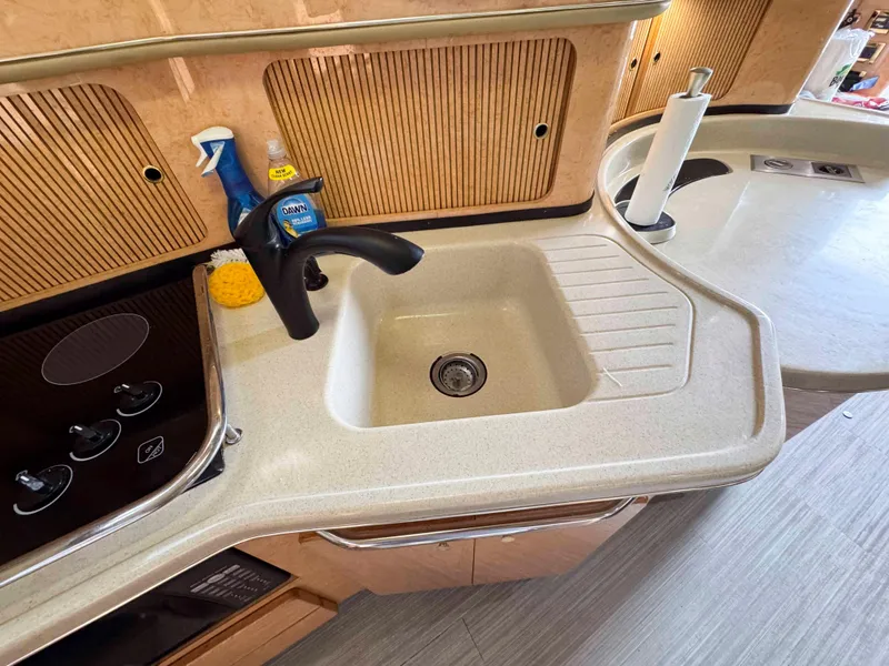 Slide: The Image of 1998 Sea Ray 440 Express Bridge kitchen sink with faucet and cleaning supplies. - 23