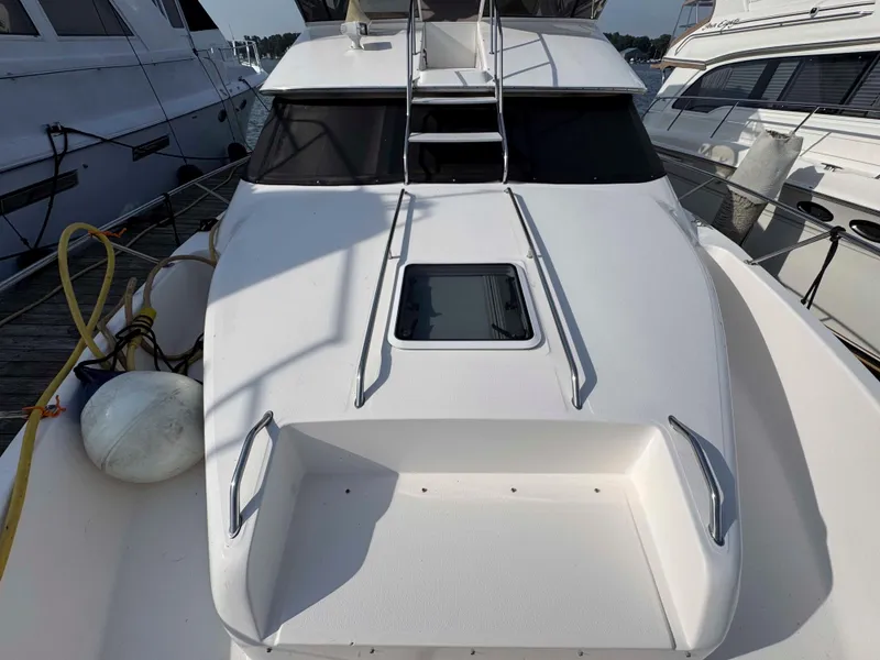 Slide: The Image of 1998 Sea Ray 440 Express Bridge yacht docked, featuring sleek white deck and tinted windows. - 7