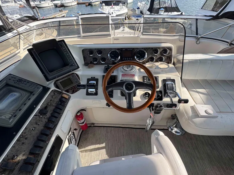 Slide: The Image of 1998 Sea Ray 440 Express Bridge helm with wooden steering wheel and navigation controls. - 9
