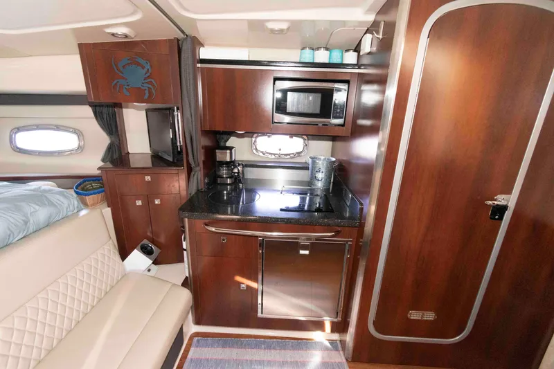 Slide: The Image of 2014 Chaparral 310 Signature yacht interior with kitchenette, microwave, and seating area. - 20