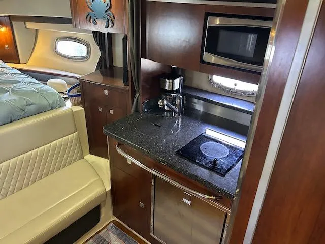 Slide: The Image of 2014 Chaparral 310 Signature yacht interior with kitchenette, featuring stove, microwave, and seating area. - 21