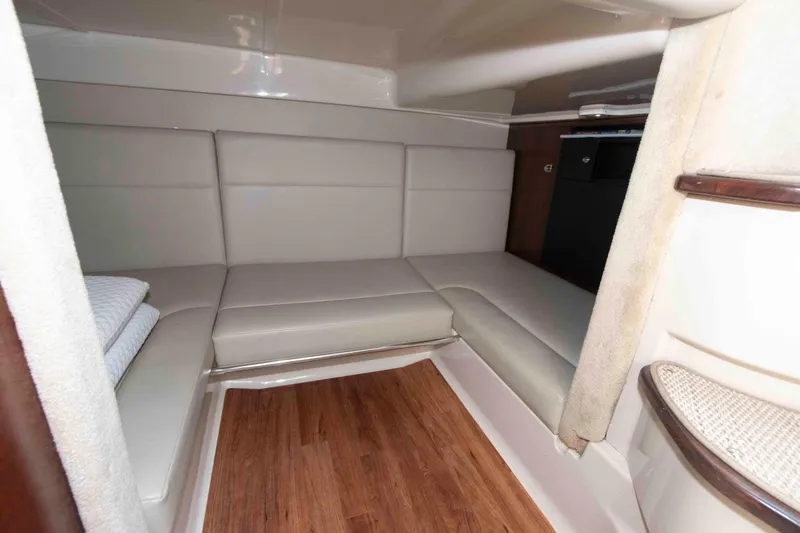 Slide: The Image of 2014 Chaparral 310 Signature cabin interior with beige seating and wooden flooring. - 22
