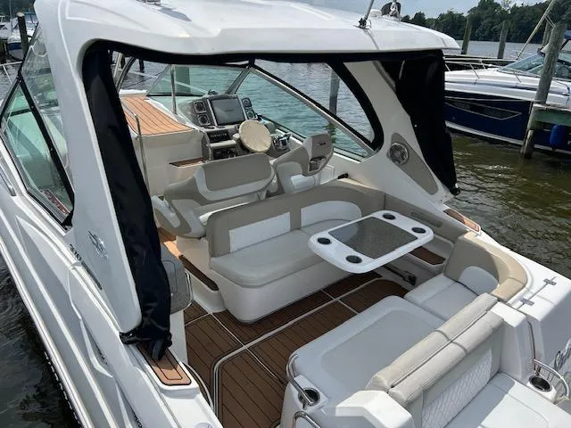 Slide: The Image of 2014 Chaparral 310 Signature boat with spacious seating and modern dashboard, docked by the water. - 4