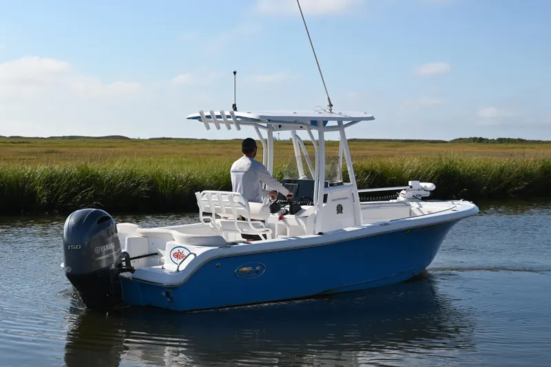 Slide: The Image of 2021 Sea Hunt Ultra 219 boat cruising on a calm waterway with grassy banks. - 10