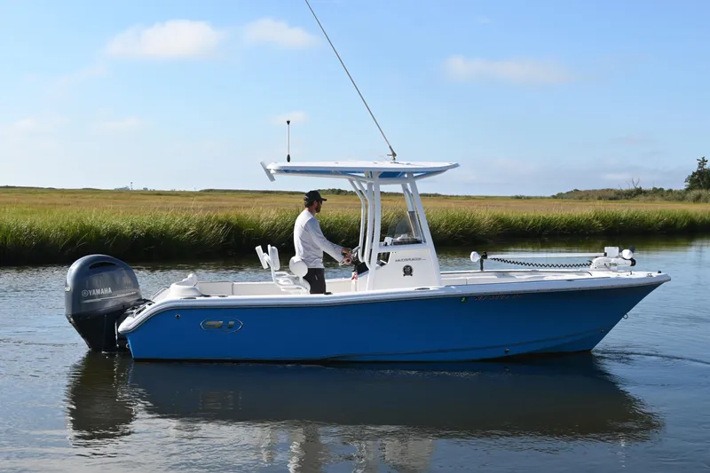 Slide: The Image of 2021 Sea Hunt Ultra 219 boat on calm water with a person steering. - 11