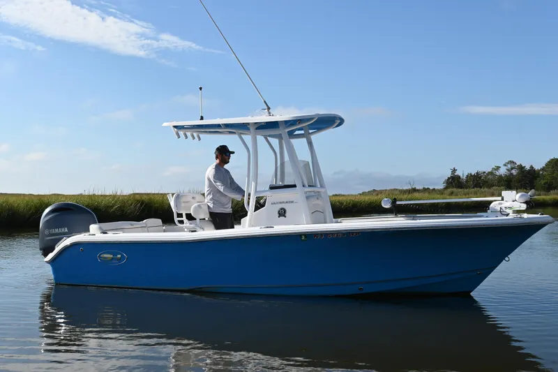 Slide: The Image of 2021 Sea Hunt Ultra 219 boat on calm water, featuring a sleek blue design. - 12