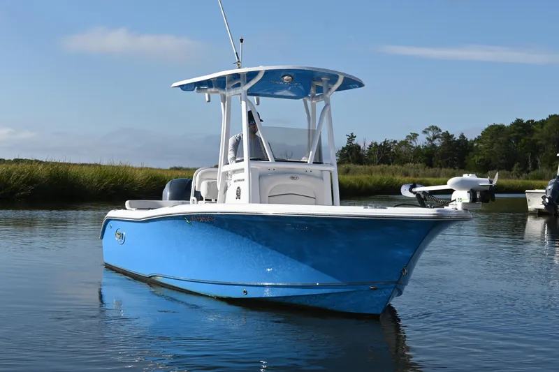 Slide: The Image of 2021 Sea Hunt Ultra 219 boat in calm water, blue hull, clear sky background. - 2