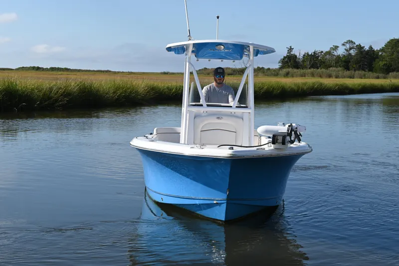 Slide: The Image of 2021 Sea Hunt Ultra 219 boat navigating a calm waterway with grassy banks. - 3