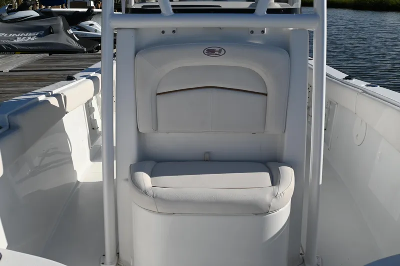 Slide: The Image of 2021 Sea Hunt Ultra 219 boat interior with cushioned seating, docked near water. - 30