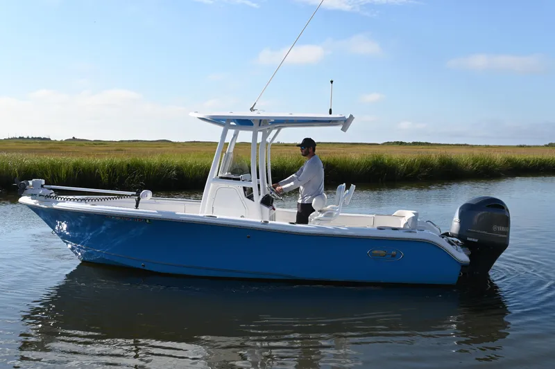 Slide: The Image of 2021 Sea Hunt Ultra 219 boat on calm water with a person steering. - 6