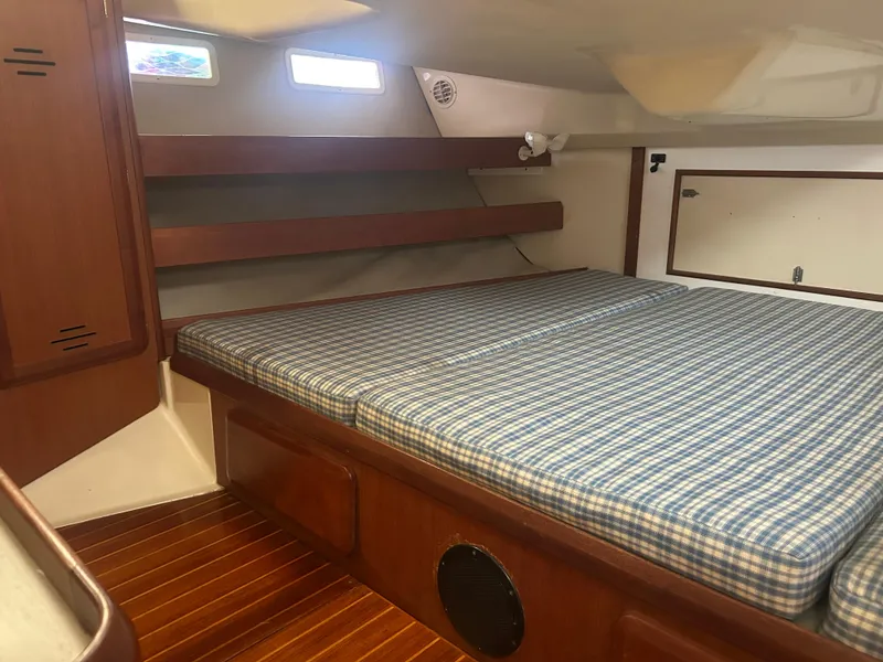 Slide: The Image of 1994 Hunter Legend 40.5 yacht interior with checkered bedding and wooden accents. - 10