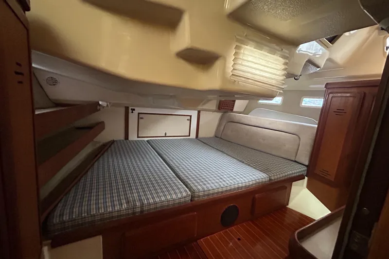 Slide: The Image of 1994 Hunter Legend 40.5 yacht cabin with bed, wooden flooring, and storage. - 15