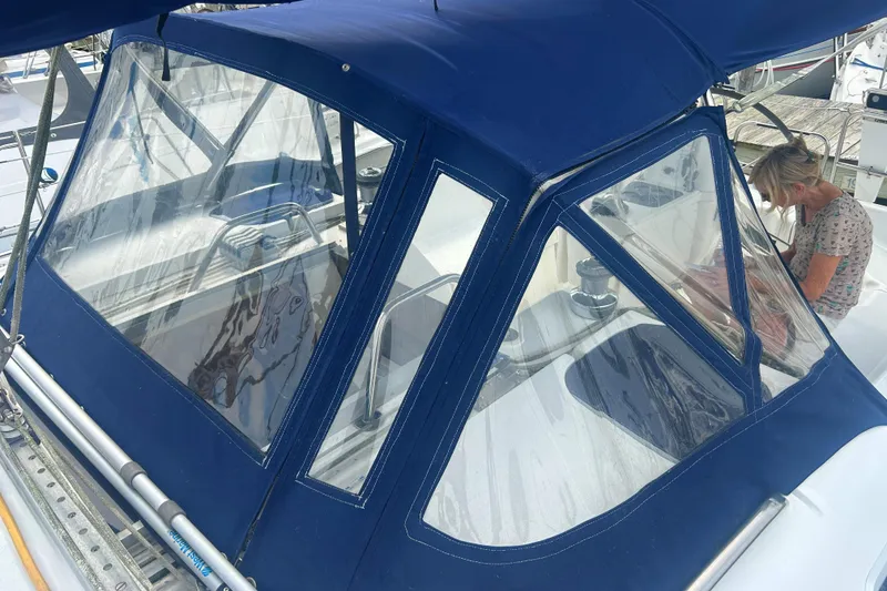 Slide: The Image of 1994 Hunter Legend 40.5 sailboat with blue canvas cover and clear windows in marina. - 21