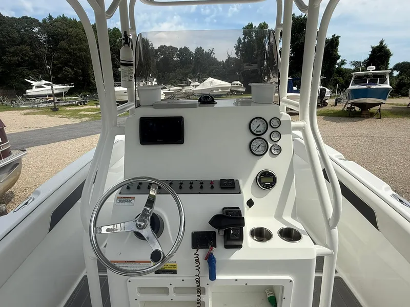 Slide: The Image of 2018 Clearwater 2200CC boat console with steering wheel and gauges in a marina setting. - 11