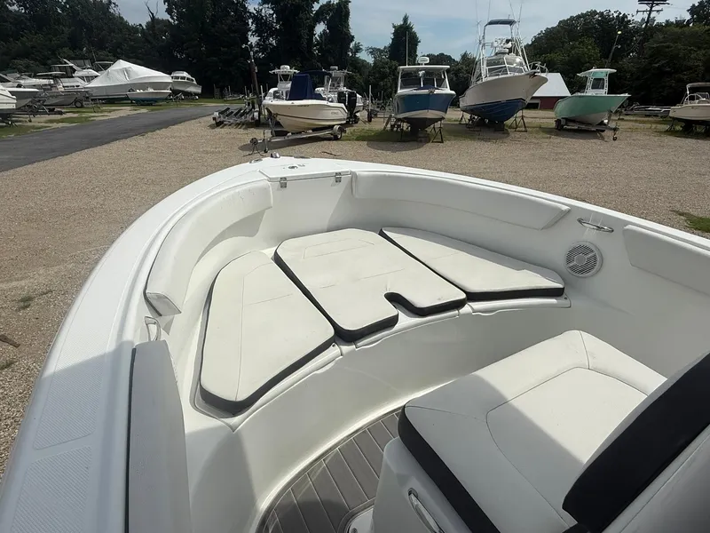 Slide: The Image of 2018 Clearwater 2200CC boat interior with cushioned seating, parked among other boats. - 13