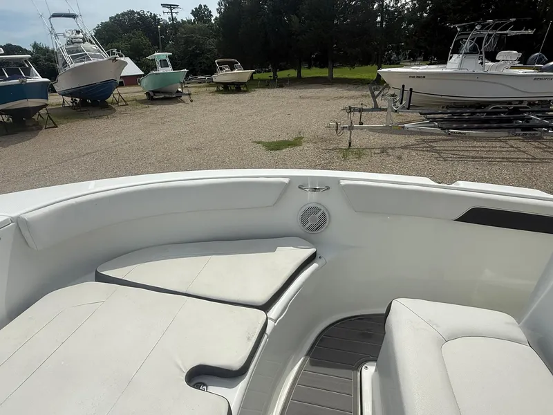 Slide: The Image of 2018 Clearwater 2200CC boat interior with cushioned seating, parked among other boats. - 14