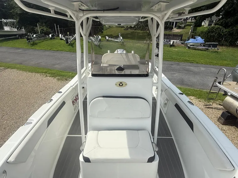 Slide: The Image of 2018 Clearwater 2200CC boat interior with seating and console, parked on gravel near grass. - 17