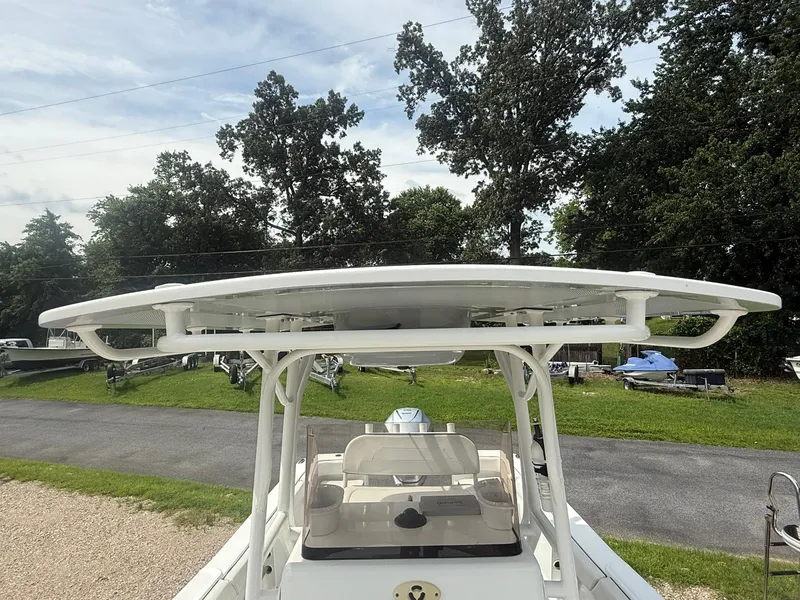 Slide: The Image of 2018 Clearwater 2200CC boat with T-top, parked outdoors, surrounded by trees and grass. - 18