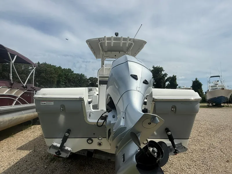 Slide: The Image of 2018 Clearwater 2200CC boat with outboard motor, parked on gravel, surrounded by trees and other boats. - 9