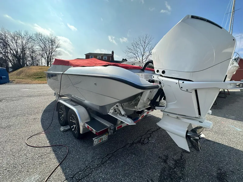 Slide: The Image of 2022 Velocity 290 SC boat on trailer with outboard motor, parked outdoors. - 9