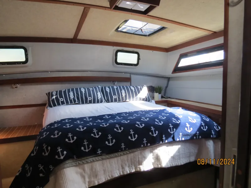 Slide: The Image of 1983 Silverton 40 Aft Cabin interior with nautical-themed bedding and natural light. - 11