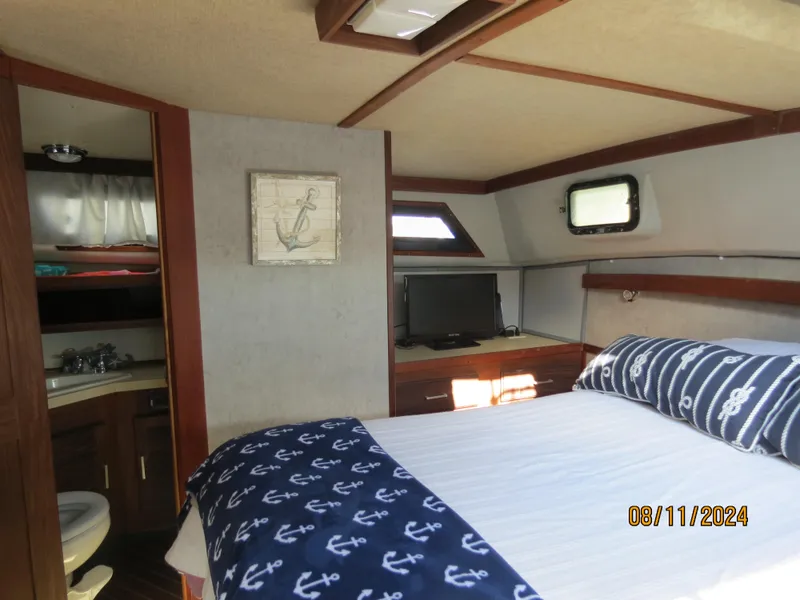 Slide: The Image of 1983 Silverton 40 Aft Cabin interior with bed, TV, and nautical decor. - 13