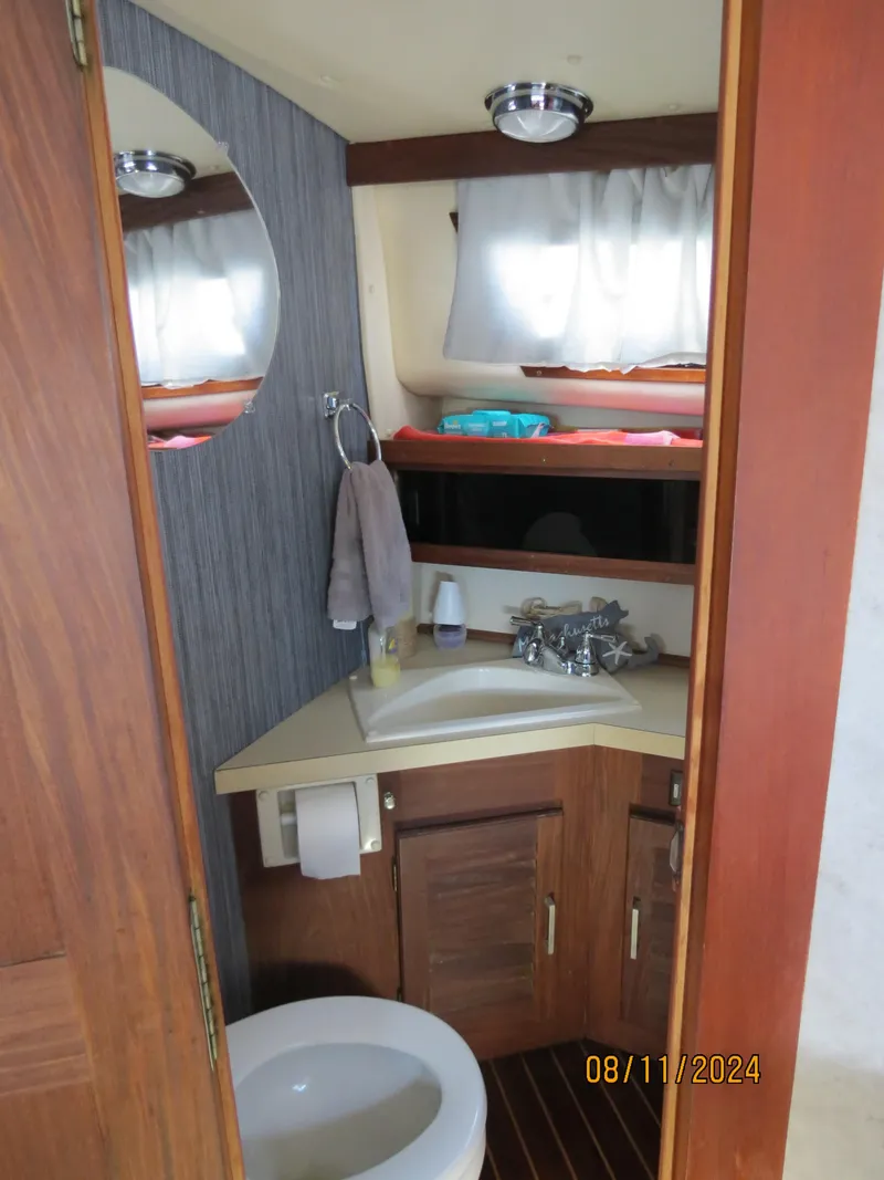 Slide: The Image of 1983 Silverton 40 Aft Cabin bathroom with sink, mirror, and wooden cabinetry. - 19
