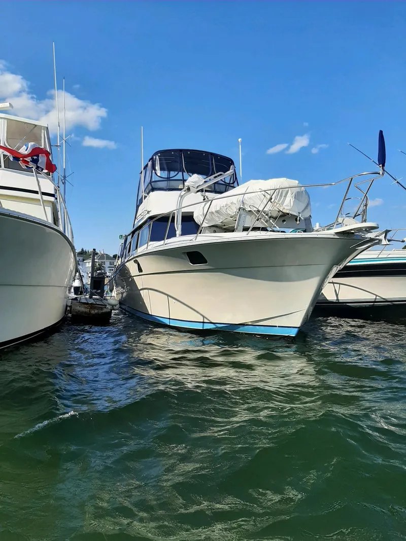 Slide: The Image of 1983 Silverton 40 Aft Cabin yacht docked between boats on a sunny day. - 2