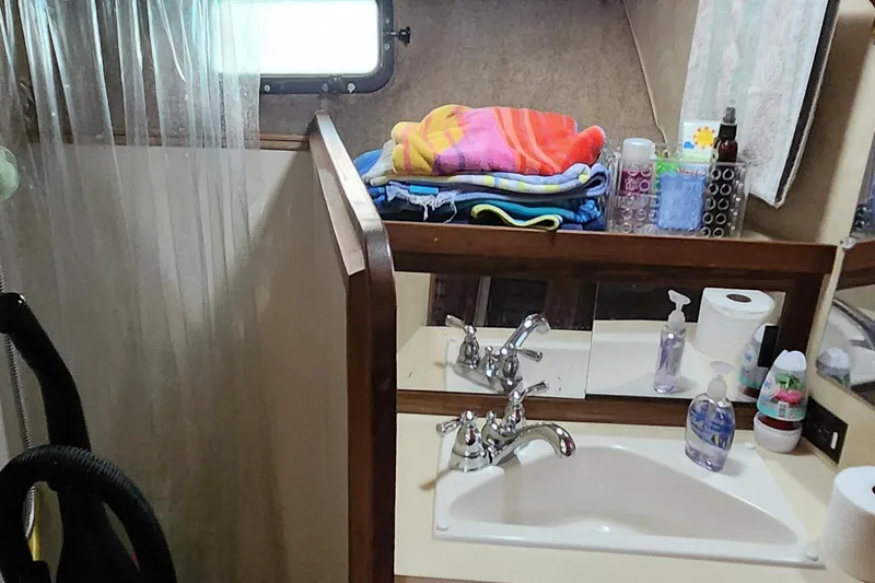 Slide: The Image of 1983 Silverton 40 Aft Cabin bathroom with sink, mirror, and toiletries. - 22