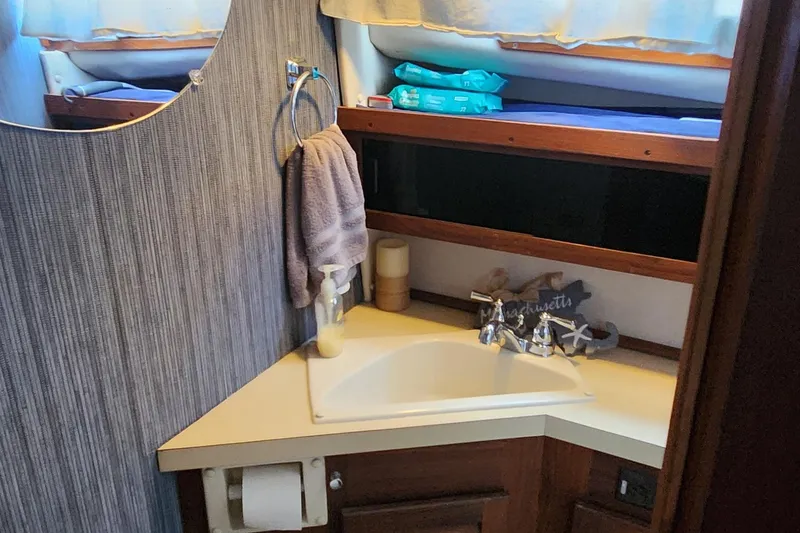 Slide: The Image of 1983 Silverton 40 Aft Cabin bathroom with sink, mirror, and toiletries. - 26