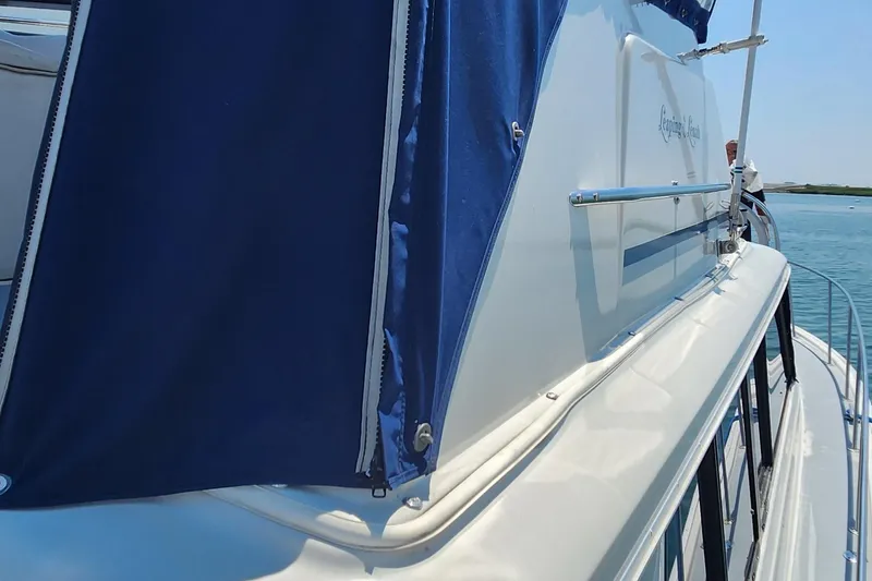 Slide: The Image of 1983 Silverton 40 Aft Cabin yacht with blue canopy, docked on calm water. - 5