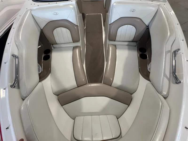 Slide: The Image of 2003 Regal 2200 boat interior with beige and white seating, featuring cup holders and chrome handles. - 14