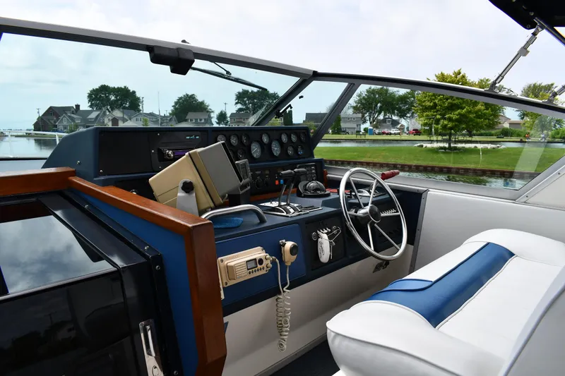Slide: The Image of 1989 Sea Ray 390 Express Cruiser helm with steering wheel and control panel, docked by a canal. - 12