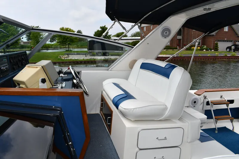 Slide: The Image of 1989 Sea Ray 390 Express Cruiser interior with white and blue seating, docked by a canal. - 18