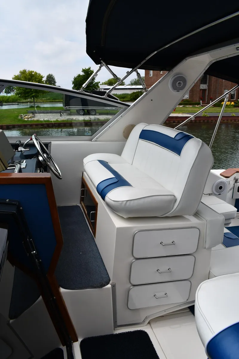 Slide: The Image of 1989 Sea Ray 390 Express Cruiser interior with white and blue seating, docked by a canal. - 19