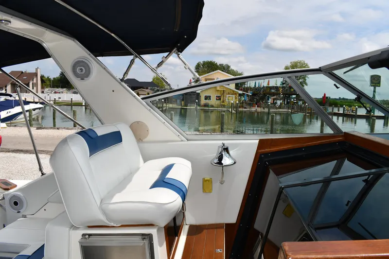 Slide: The Image of 1989 Sea Ray 390 Express Cruiser interior with white seating, dockside view, and blue accents. - 20