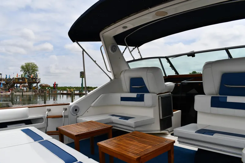 Slide: The Image of 1989 Sea Ray 390 Express Cruiser with white and blue seating, docked by a scenic waterfront. - 24