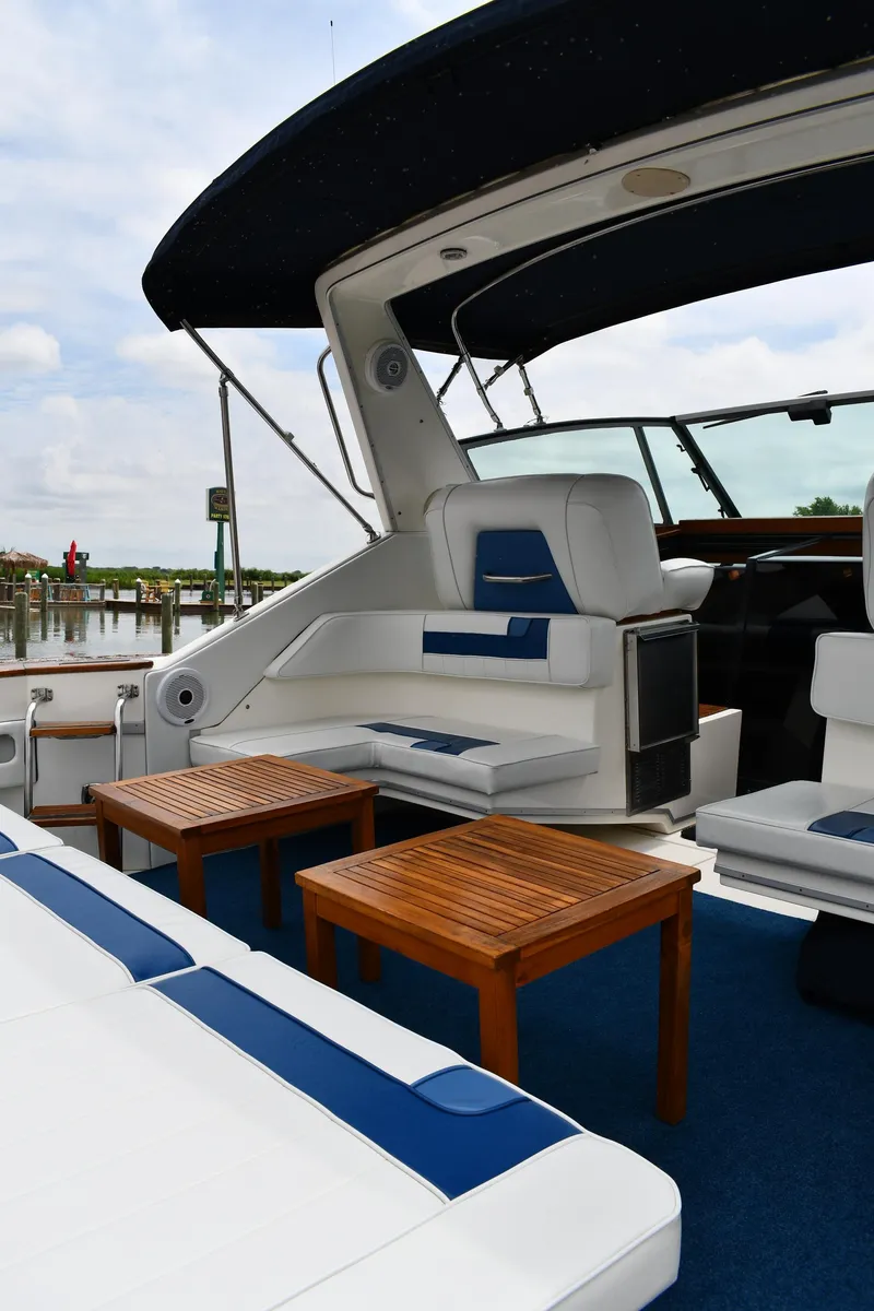 Slide: The Image of 1989 Sea Ray 390 Express Cruiser with blue and white seating, wooden tables, and marina backdrop. - 25