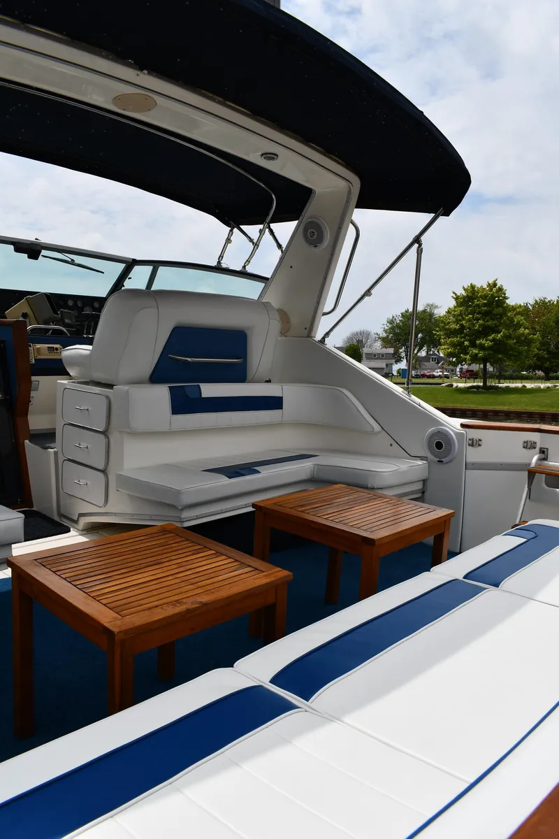 Slide: The Image of 1989 Sea Ray 390 Express Cruiser with white and blue seating, wooden tables, and canopy. - 27