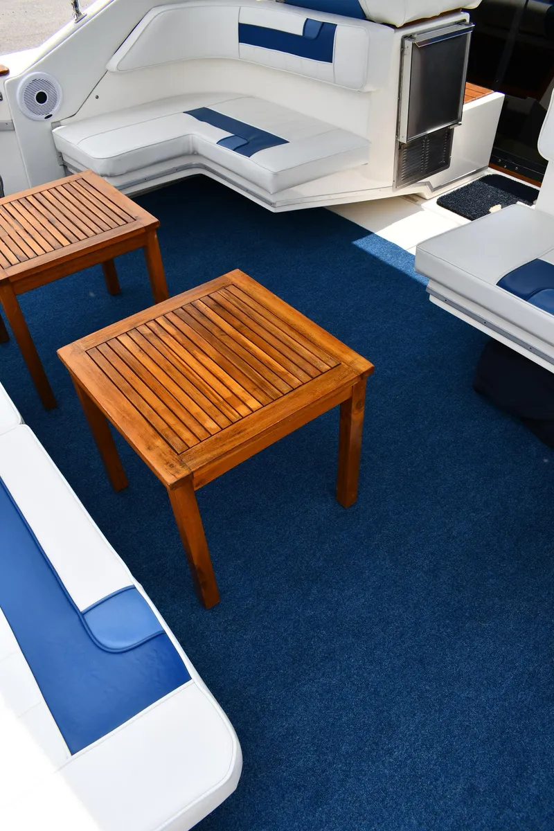 Slide: The Image of 1989 Sea Ray 390 Express Cruiser interior with blue carpet, white seating, and wooden tables. - 29
