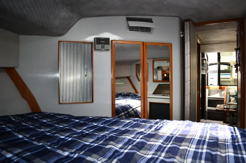 Slide: The Image of 1989 Sea Ray 390 Express Cruiser cabin with plaid bedding and mirrored closet. - 35
